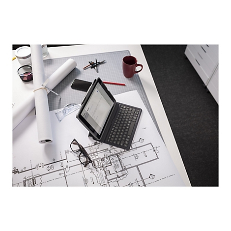 Ein Tablet mit angebrachtem Keyboard liegt auf einem Tisch. Auf dem Tablet-Bildschirm ist ein E-Mail-Entwurf zu sehen. Auf dem Tisch sind weitere Gegenstände zu sehen, darunter Baupläne, eine Tasse, eine Brille und Bürobedarf.