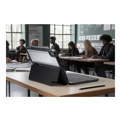 Ein Tablet mit Tastatur in einem Klassenzimmer. Auf einem Tisch liegen Stifte und Notizen. Im Hintergrund sitzen Schüler.