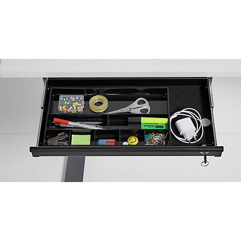 Geöffnete schwarze Schublade mit Bürobedarf: Stifte, Schere, Klebeband, Reißzwecken, Ladekabel, Marker und Notizen.