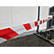 Rot-weiß gestreiftes Absperrband spannt sich diagonal vor einer weißen Hauswand.