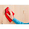 A hand wiping a wooden wall with a red cloth. A door handle can be seen in the background.