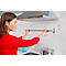 Woman installing a towel rack in the kitchen. She's wearing a red top. In the background, a hood and cooking utensils.
