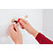 Person attaching wall hooks with red tool to a white wall.