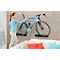 Woman hanging a bicycle on a wall mount. Light blue bike with 'De Rosa' lettering, gray wall, white sofa.