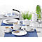 Coffee set with cups, saucers, milk jug and sugar bowl on a table. Plants can be seen in the background.