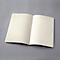 Carnet ligné ouvert sur fond gris. Les pages sont de couleur crème.