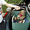Person lifting a basket full of toys out of the trunk of a car.