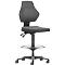 Black ergonomic chair, height-adjustable, with footrest and castors. Backrest and seat are padded.