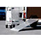 Grey roll cage next to an extended loading ramp of a delivery van.