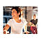 Eine lächelnde Frau trainiert auf einem Heimtrainer im Fitnessstudio und trägt weiße In-Ear-Kopfhörer.