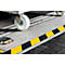 Close-up of a loading ramp with warning markings, wheelchair wheel, and a lighted obstacle.