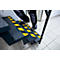 Person climbing stairs with yellow and black markings. Metal railing.