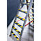 Aluminum ladder with black and yellow stripes on the steps, standing in a room with a dark wall.