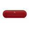 Enceinte Beats Pill+ rouge, design ovale, surface perforée. Logo "b" argenté. Le fond est blanc.