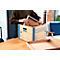 Person legt einen weissen Bilderrahmen in eine braune Archivbox. Vorne liegt eine leere Box.