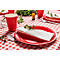 Table dressée avec une assiette en papier rouge, une serviette et un gobelet sur une nappe à carreaux. Décorée d'herbes.