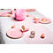 Une table dressée de manière festive avec des assiettes, des tasses et des décorations roses. Un chemin de table rose et une grande boule en papier sont sur la table.