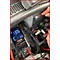 Ein Multimeter zeigt 13,06 V an, während es die Spannung in einem Fahrzeug misst. Im Hintergrund sind Sicherungskasten und Hände zu sehen.