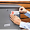 Person sticking a stop-advertising sticker on a mailbox. Sticker shows a red stop symbol, with 'Bitte' below.