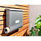 Grey mailbox on a wooden slat wall with newspaper. To the right a shrub. The box says 'primcore'.