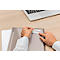 Person sticking a sticker labeled "CORE" onto a gray folder. A laptop rests on the table.