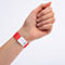 Un bracelet d'identification rouge avec une zone blanche et le numéro 047800 au poignet.