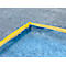 Coin d'une bâche bleue avec un bord jaune, sur une surface grise.