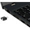 Ein schwarzer USB-C-Adapter neben einem Laptop. Der Adapter und die Laptop-Seite sind im Detail zu sehen, mit Tastatur und Anschlüssen.
