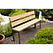 Banc en bois dans le jardin, avec cadre en métal. Derrière, un petit étang et des buissons verts.