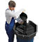 A man in blue overalls pours black liquid from a bucket into a drip tray.