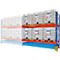 Regalsystem mit weißen IBC-Tanks. Orangefarbene Regale, blaue Auffangwanne. Die Tanks stehen auf Paletten.