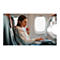 Femme dans un avion, avec un casque et un ordinateur portable. Elle tape, regarde en bas, avec une fenÃªtre en arriÃ¨re-plan.