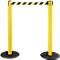 Yellow stanchions with black and yellow striped barrier tape. Both stanchions stand on black, round bases.