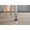 Close-up of a chrome chair leg on light wood. A shadow is visible on the floor.