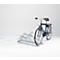 A blue bicycle stands in a metal bicycle rack against a white background.