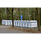 A row of white bicycle garages with blue signs. A parking sign stands in front of a forest background.