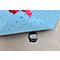 A blue absorbent mat with small dark dots covers a spill. A hand in a pink glove lifts the mat.
