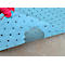 A blue absorbent pad with dark dots, on which there is a wet spot. A hand in a red glove holds the fleece.