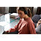 Woman with headphones focused on tablet, sitting on sofa. Background: couch, table and books.