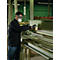 Un homme portant des lunettes de protection et un masque travaille le bois sur une machine dans un atelier.