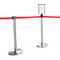 Two silver stanchions with a red ribbon between them, one with a sign.