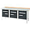 Workbench with gray work surface and three drawers. The drawers are dark gray with silver handles. The table legs are silver, the edge is made of wood.
