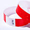 Un bracelet d'identification rouge en papier avec des gouttes d'eau et le numéro 047799 imprimé.