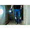 Person mit blauer Hose und Handschuhen hält eine Arbeitslampe. Der helle Lichtkegel erhellt einen grauen Raum.