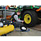 Man inflating tractor tire with compressed air. Yellow compressor and green tractor in the background.