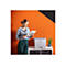 Frau betrachtet Dokument neben Drucker. Aufdruck 'Digital Marketing'. Hintergrund: orange Wand mit Kreisen.