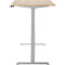 Un bureau debout avec un plateau de table brun clair, un cadre gris et deux repose-pieds.