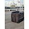 Black rolling suitcase on wooden planks. City view in the background.
