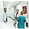 Trois professionnels de santé discutent dans un couloir d'hôpital lumineux à côté d'une affiche de don de sang.