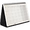 Calendrier de bureau ouvert en avril. Support noir, pages blanches avec carrés noirs. Reliure spirale en haut.